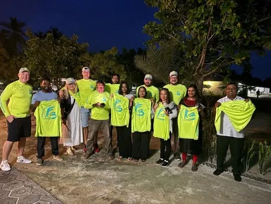 Tým Friendly Maldives s místními obyvateli během večerního setkání, všichni v tričkách s logem FM