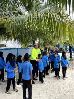 Zástupce Friendly Maldives s místními školními dětmi pod palmami na ostrově