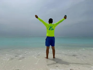 Místní obyvatel v tričku Friendly Maldives na pláži s výhledem na Indický oceán